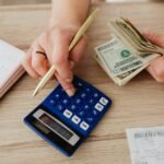 Hands handling cash and calculator for budget planning. Modern financial scene.